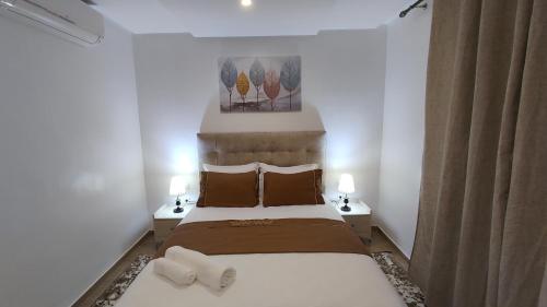 乌季达DLX02 - Appartement Deluxe 2 chambres - Centre Ville Oujda的一间卧室配有一张大床,桌子上放着两盏灯