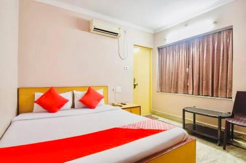普里Hotel Falcon House ! Puri - ViDi Group的一间卧室配有一张带红色枕头的床和一扇窗户