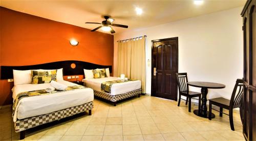 普拉亚卡门Hotel Colonial Playa del Carmen的酒店客房设有两张床和一张桌子。
