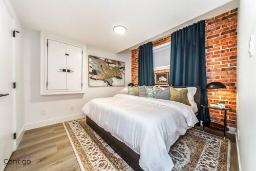 埃德蒙顿Luxe New York Style Bsmt Suite, Near DT & WEM, King Bed, WiFi的卧室配有白色的床和砖墙