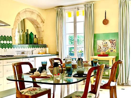 贝尔热拉克Le Logis Plantagenêt的厨房配有玻璃桌和椅子