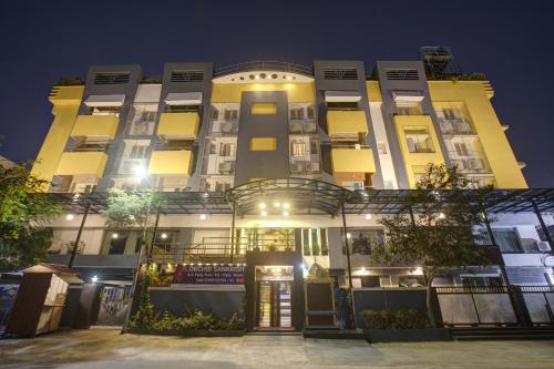 钦奈Townhouse Orchid Sankrish Near Balaji Dental College的一座高大的黄色建筑,晚上灯亮