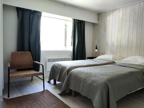拉彭兰塔Cozy cottage in Pontus的一间卧室设有两张床、一把椅子和一个窗户。