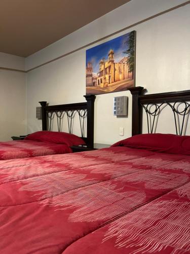 阿亚库乔THIZMA HOTELES Ex HotelSantaMaria的一间卧室配有两张带红色床单和绘画的床