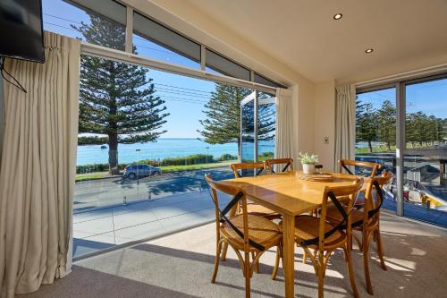 凯库拉Kaikoura Waterfront Apartments的一间带桌椅和大窗户的用餐室