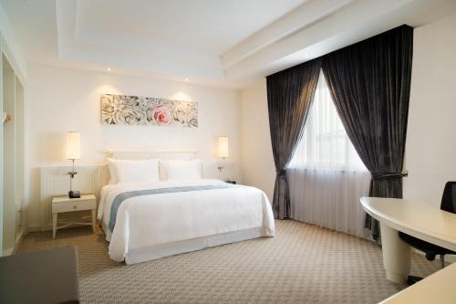 万隆万隆福朋喜来登酒店的卧室配有白色的床、书桌和窗户。