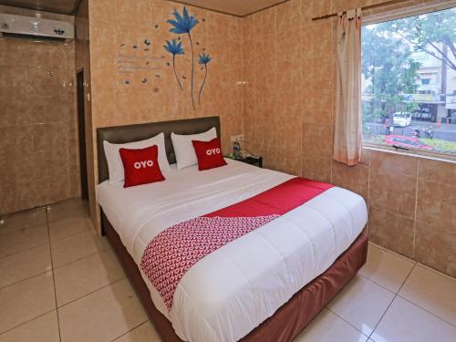 South TangerangSUPER OYO 92672 Hotel Bsd的一间卧室配有一张带红色枕头的床和一扇窗户