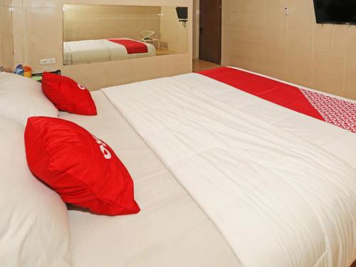 South TangerangOYO 92674 Hotel Ciputat的一张大白色的床,配有红色枕头