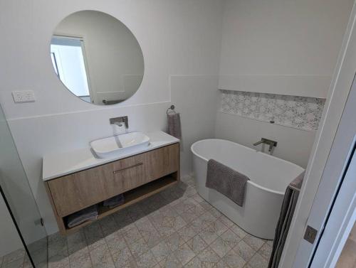 巴托湾Bateau Bay Retreat的一间带水槽、浴缸和镜子的浴室