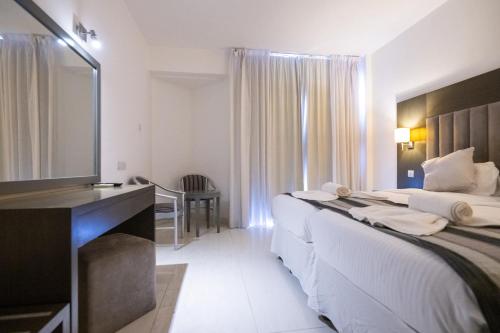 阿依纳帕Napa Jay Hotel的酒店客房设有两张床、一张桌子和一面镜子
