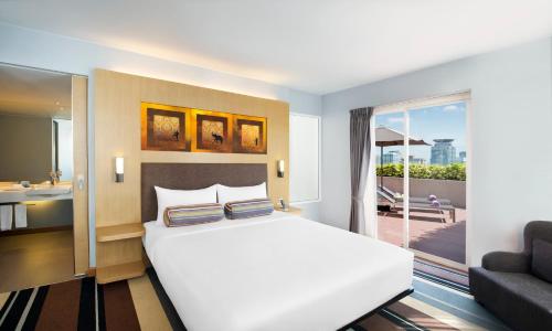 曼谷Aloft Bangkok - Sukhumvit 11的一间带白色床的卧室和一个阳台