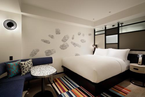 大阪Aloft Osaka Dojima的卧室配有白色的床和蓝色的沙发