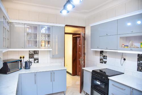 坎帕拉K-Cube Villas的厨房配有白色橱柜和黑炉。