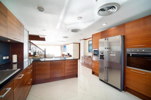 芭东海滩Patongtower Duplex Seaview4BR2902的厨房配有木制橱柜和不锈钢冰箱。