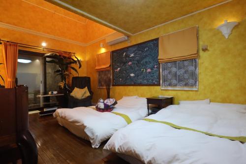 太宰府市1日1組限定Villa Dazaifu 露天風呂付1棟貸し的一间卧室设有两张床,墙上挂着一幅画
