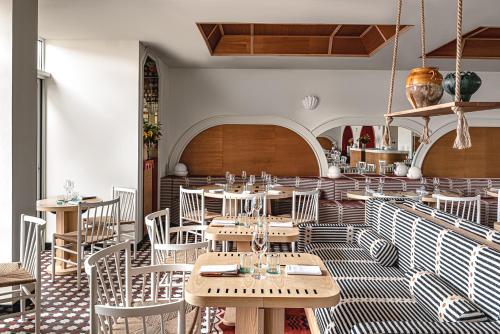 比亚里茨Regina Experimental Biarritz的配有木桌和白色椅子的餐厅
