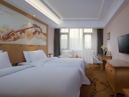运城维也纳酒店山西运城槐东路店的酒店客房设有两张床和一台平面电视。
