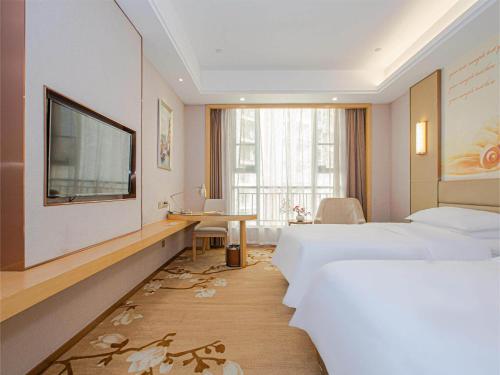 南昌维也纳国际酒店南昌青山湖万达广场店的酒店客房设有两张床、一张桌子和一台电视。