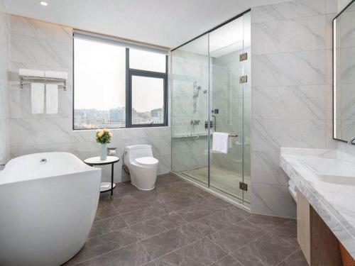 宝安凯里亚德酒店(深圳机场固戍地铁站店)的带浴缸、卫生间和淋浴的浴室。