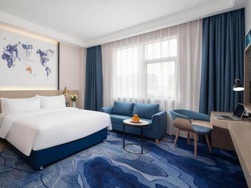 宝安凯里亚德酒店(深圳机场固戍地铁站店)的酒店客房,配有床和蓝色的沙发