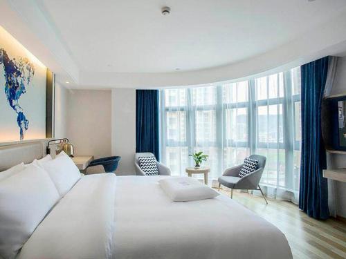 霞浦凯里亚德酒店(霞浦高铁站店)的酒店客房带大型白色床和椅子