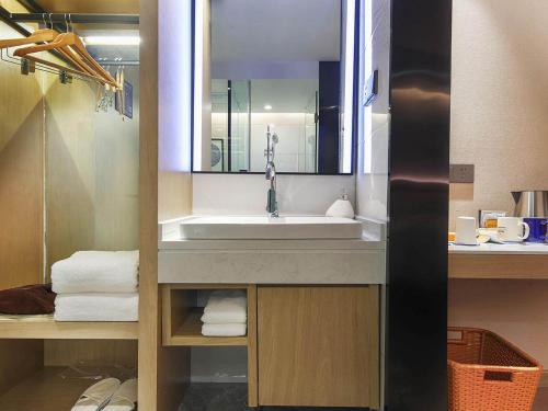 信阳凯里亚德酒店(信阳平桥店)的浴室配有盥洗盆、镜子和毛巾