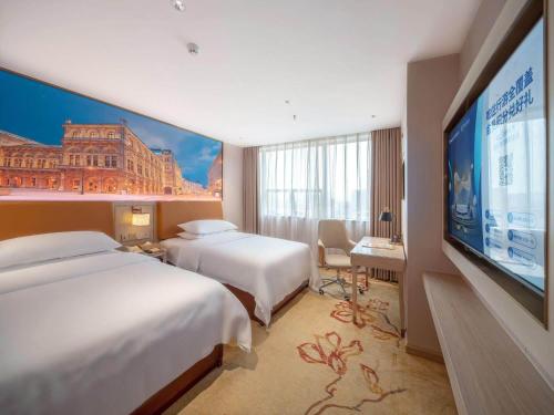 清远维也纳酒店清远城市广场连江路店5.0的酒店客房设有两张床和一台平面电视。