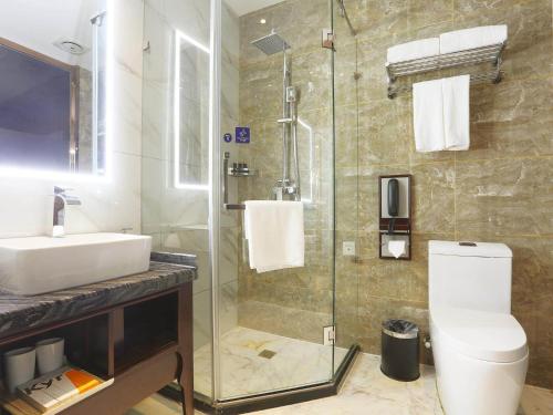 哈尔滨凯里亚德酒店哈尔滨火车站中央大街店的浴室配有卫生间、盥洗盆和淋浴。