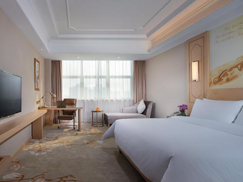 无锡维也纳国际酒店江苏无锡太湖博览中心店的酒店客房设有一张大床和一张书桌。