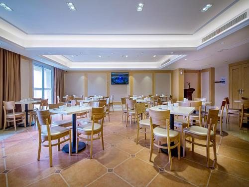 宜昌维也纳国际酒店·湖北宜昌葛洲坝三峡文化天地店的配有桌椅和讲台的用餐室