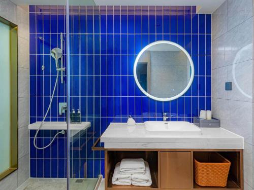九江凯里亚德酒店(九江快乐城店)的蓝色瓷砖浴室设有水槽和镜子