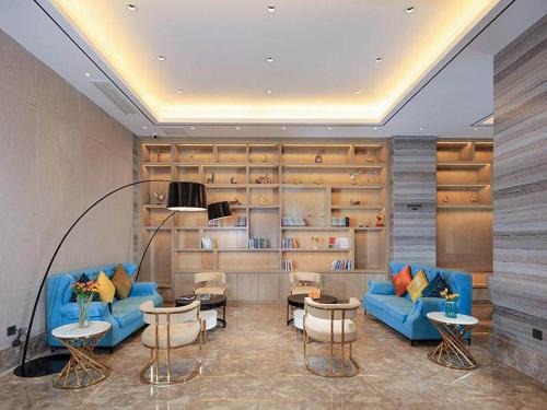 重庆凯里亚德酒店(重庆北站店)的客厅配有蓝色的沙发、桌子和书架