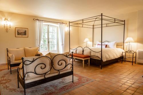 洛尔格Château les Crostes的一间卧室配有四柱床和沙发