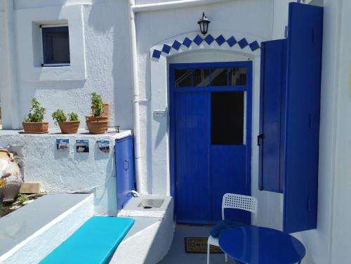 Péran TriovasálosMari...Milo的白色建筑的蓝色门,上面有桌子和蓝色桌子的四面 ⁇ 