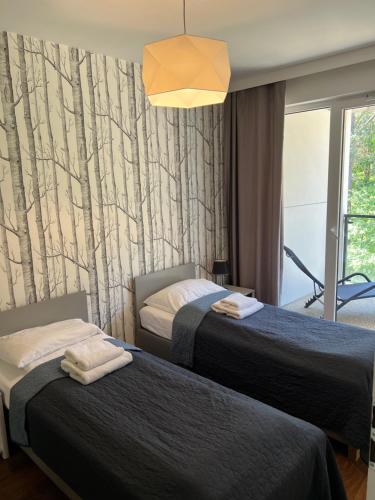 奥古斯图Sosnowe Apartamenty - Marina.的酒店客房设有两张床和窗户。