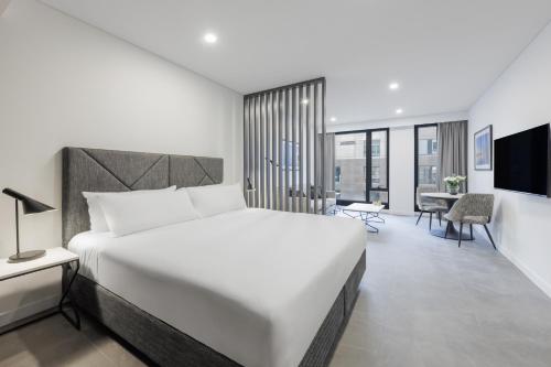墨尔本Meriton Suites King Street Melbourne的卧室配有一张白色大床和一张书桌