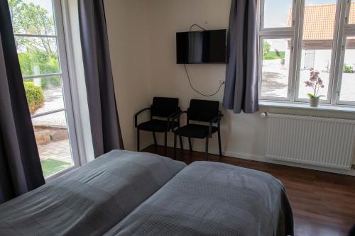OnsbjergNordgården Pension的一间卧室配有一张床、两把椅子和窗户