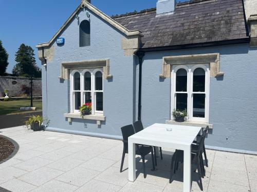 韦克斯福德Wellington Cottage的蓝色房子前面的白色桌子和椅子