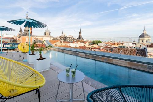 马德里Pestana Plaza Mayor Madrid的一个带桌椅的阳台和一个游泳池