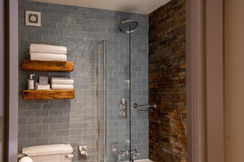普利布里奇The Crown Inn Pooley Bridge的浴室设有玻璃淋浴间、卫生间和毛巾。
