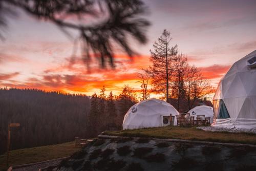 布科维纳-塔钱斯卡Tatra Glamp Bukowina Tatrzańska - Sieć noclegowa Tatra Glamp的一组帐篷,背景是日落