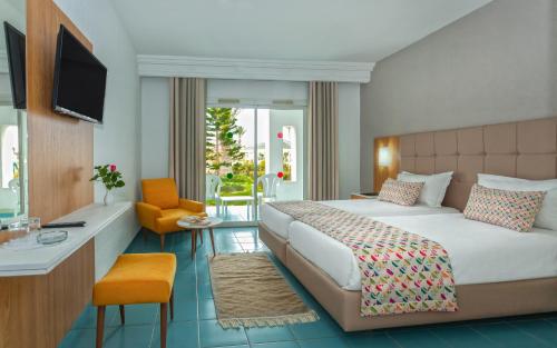 米多恩杰尔巴假日海滩酒店的一间卧室配有一张床、一张书桌和一台电视。