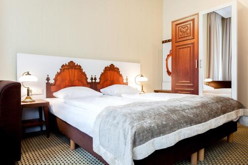 科沃布热格Jantar Hotel & SPA by Zdrojowa的一间卧室配有一张大床和木制床头板
