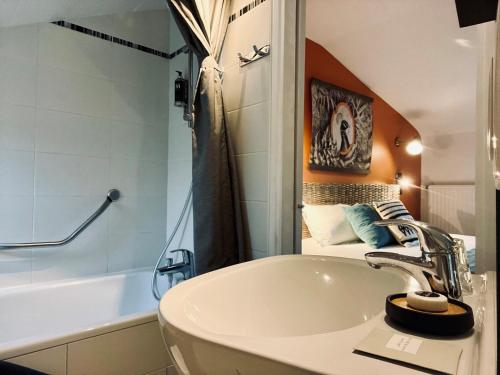 多维尔Hotel Le Patio - Deauville的浴室配有盥洗盆和浴缸。