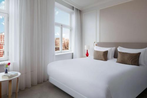 阿姆斯特丹Tivoli Doelen Amsterdam Hotel的白色的卧室设有一张白色大床和一个窗户。