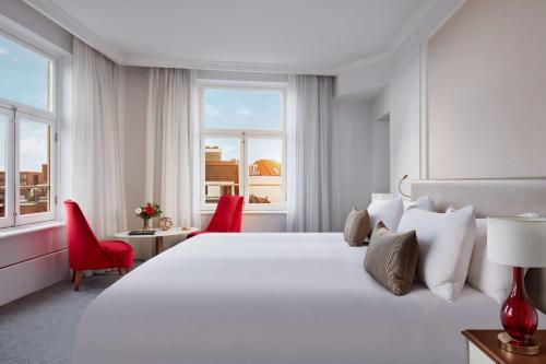 阿姆斯特丹Tivoli Doelen Amsterdam Hotel的卧室配有白色大床和红色椅子