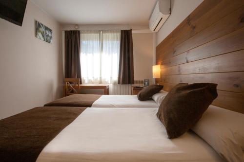 马萨纳Hotel Màgic La Massana的酒店客房设有两张床和窗户。