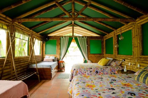 瓜杜阿斯Aguas Claras Bamboo Ecolodge的一间设有两张床的卧室,位于带绿色墙壁的房间