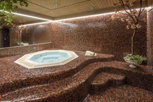坎波图雷斯加尼兹莫霍夫住宿加早餐旅馆的一间带按摩浴缸的浴室,位于马赛克墙内