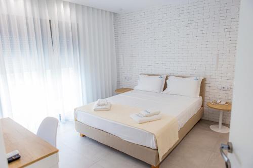 斯卡拉拉乔伊The Angeliki Boutique Hotel的白色卧室,配有带毛巾的床